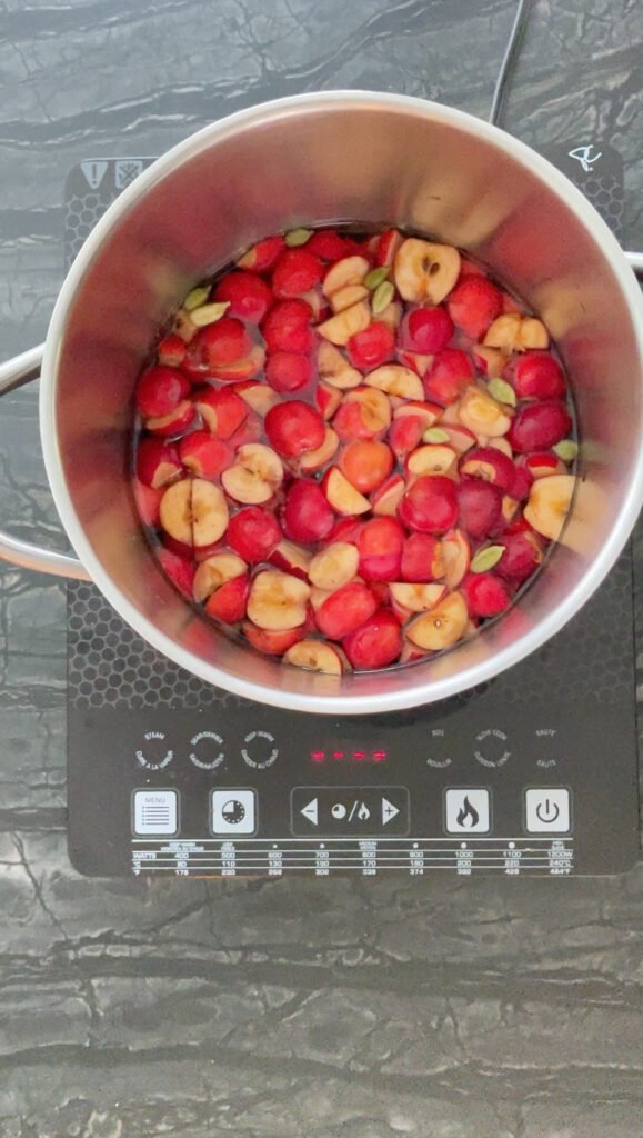 Pot of quartered crab apples in liquid on a countertop cooktop