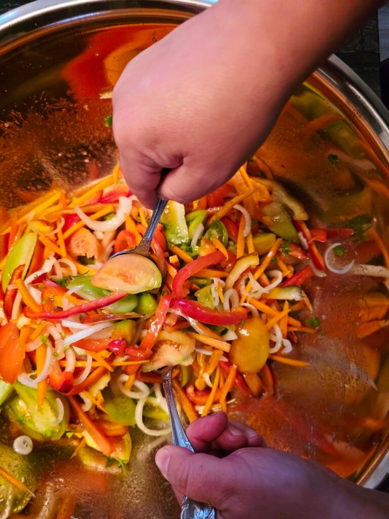 A spoon stirring chopped vegetables in a pot of liquid.